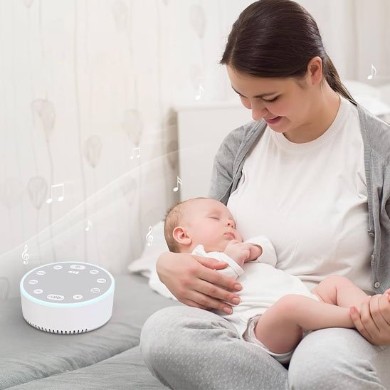 Maman tenant son bébé endormi, la veilleuse bruit blanc à proximité pour un apaisement continu.