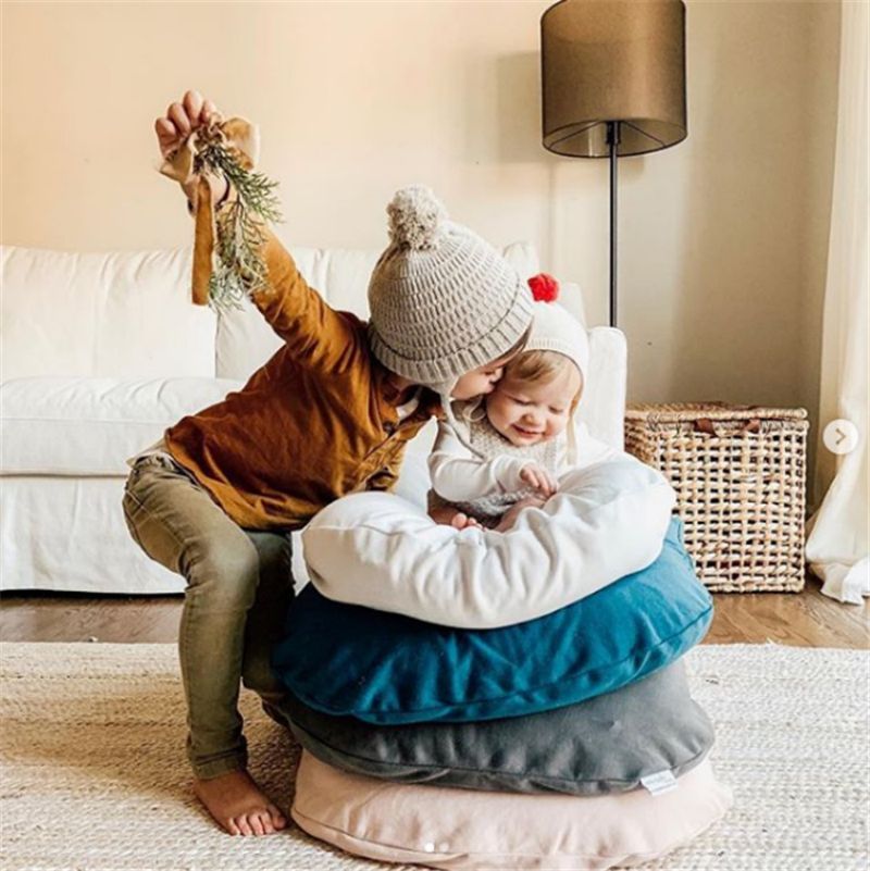 Un enfant joue avec un bébé confortablement installé dans un réducteur de lit biomimétique