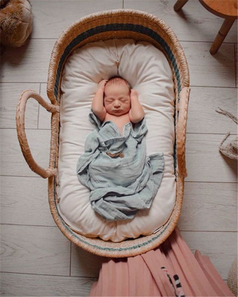 Un réducteur de lit biomimétique est placé à l'intérieur d'un panier moïse, offrant une solution de sommeil confortable et sécurisée pour un nouveau-né.