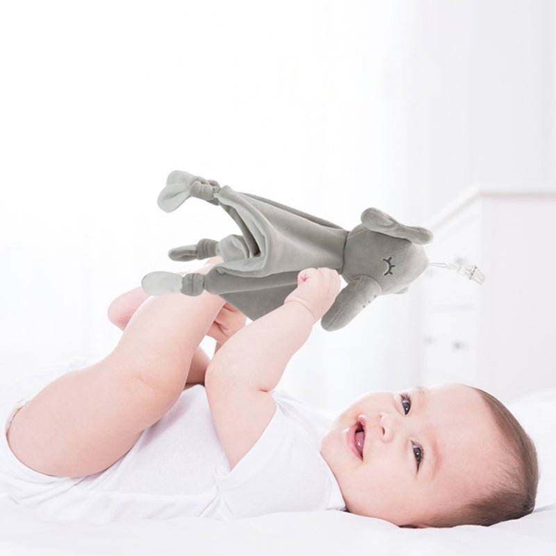 Bébé souriant jouant avec un doudou éléphant gris, moment de bonheur